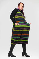 Woman wearing a colorful striped dress with a black top on a white background