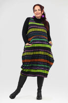 Woman wearing a colorful striped dress with a black turtleneck on a white background