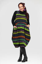 Woman wearing a colorful striped dress with a black turtleneck underneath on a white background